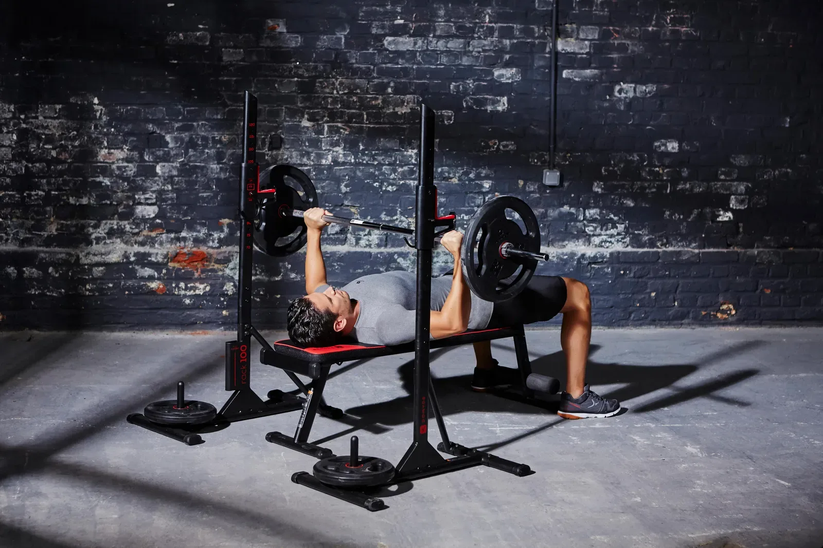 Person doing a bench press under a squat rack in a home gym
