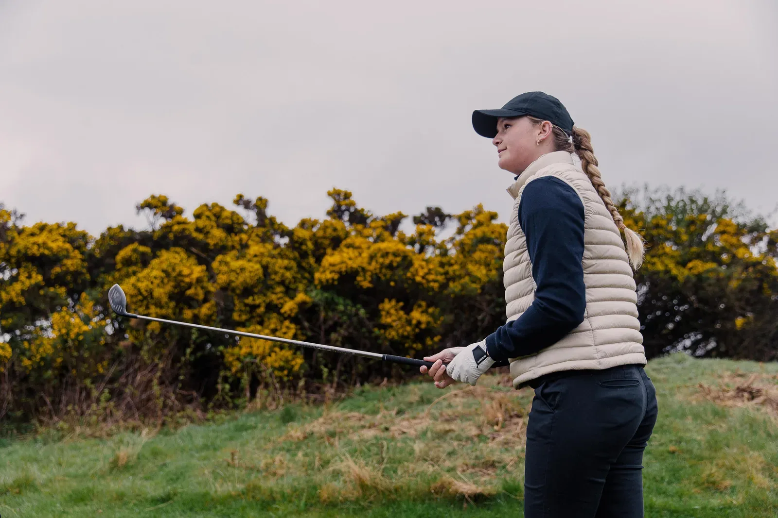 Golfer holding her club and watching the shot after her swing