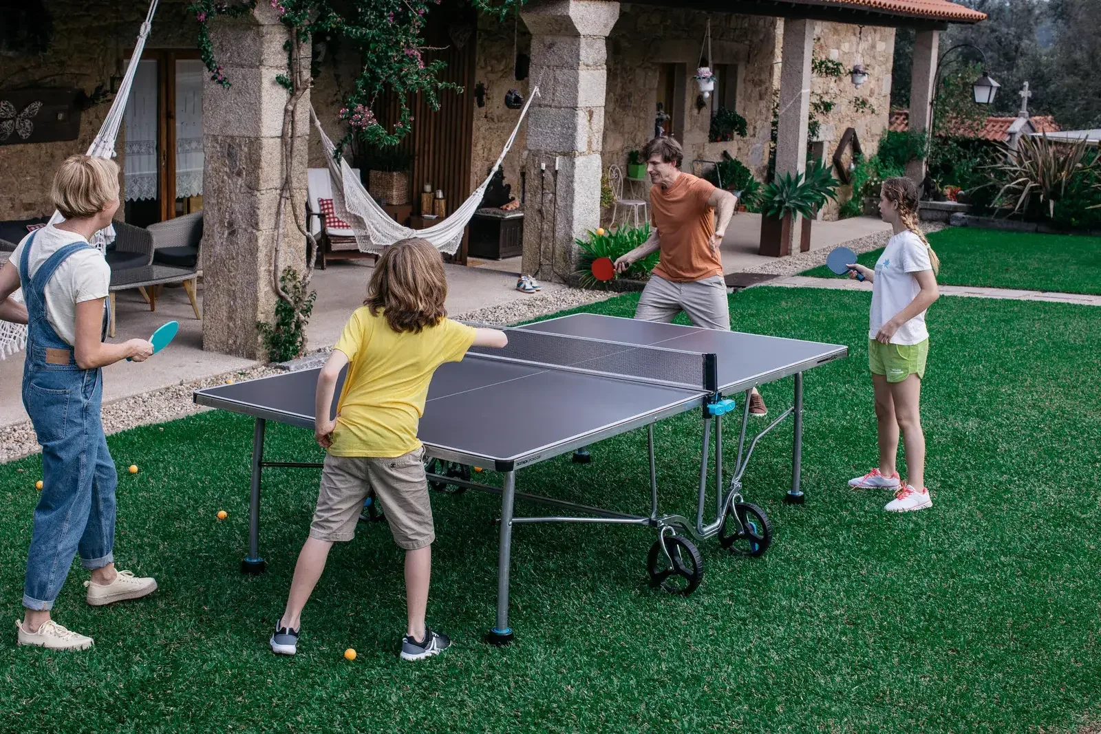 Kids rallying on an outdoor table tennis table in a garden