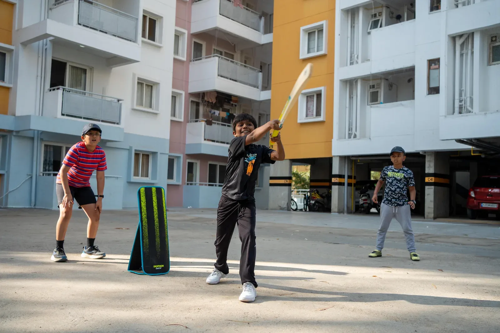 Kids playing street cricket with a batter in front of a set of stumps
