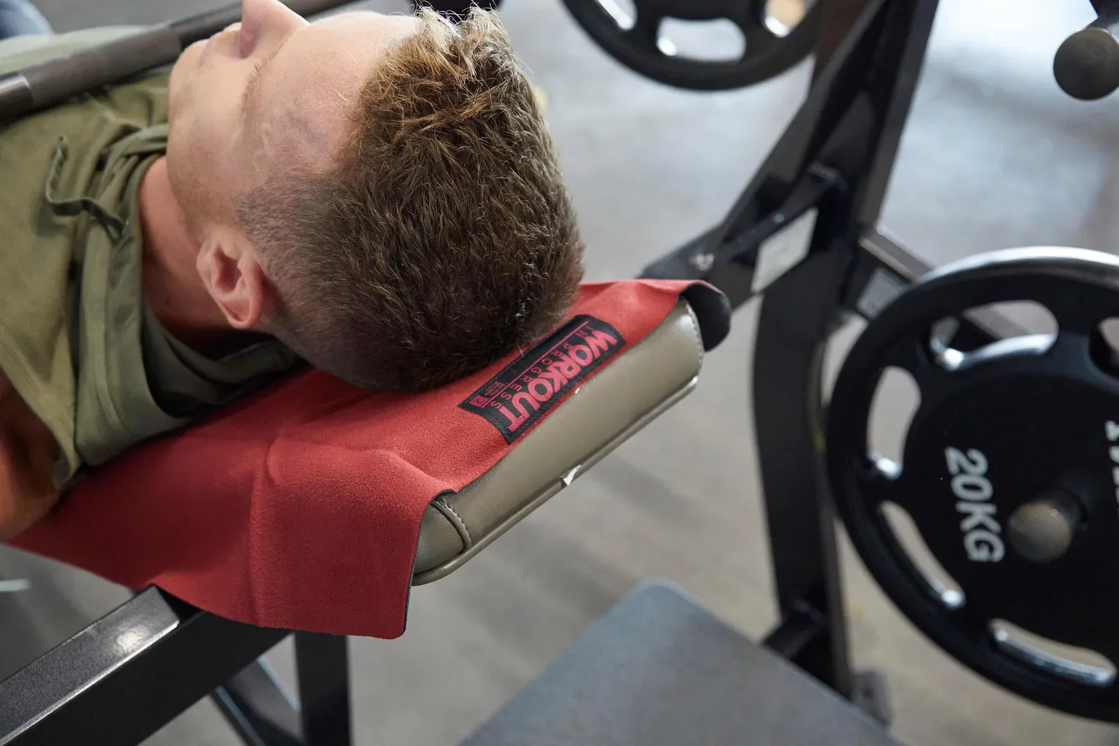 Man catching his breath on a weight bench with a towel under his head