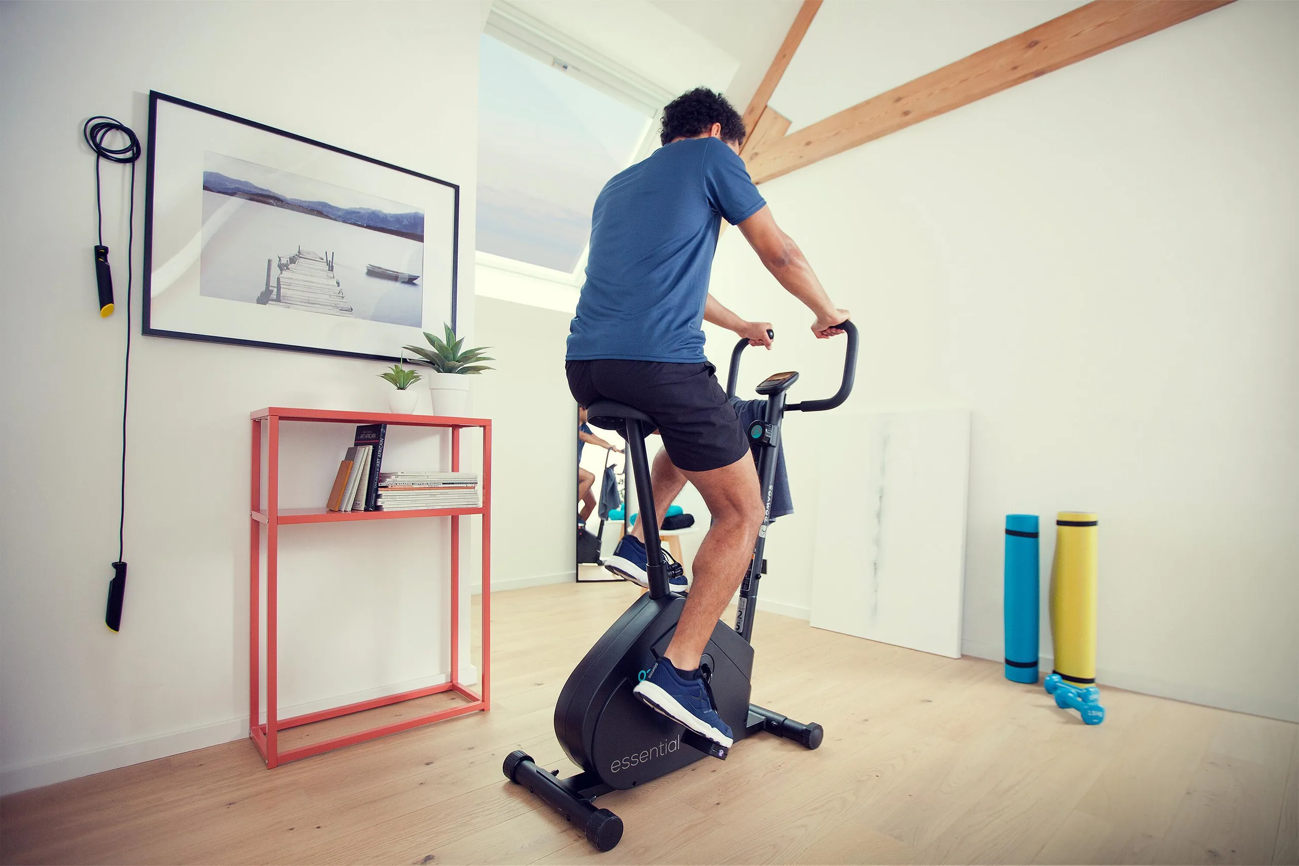 Man pedalling an exercise bike in a bright room at home