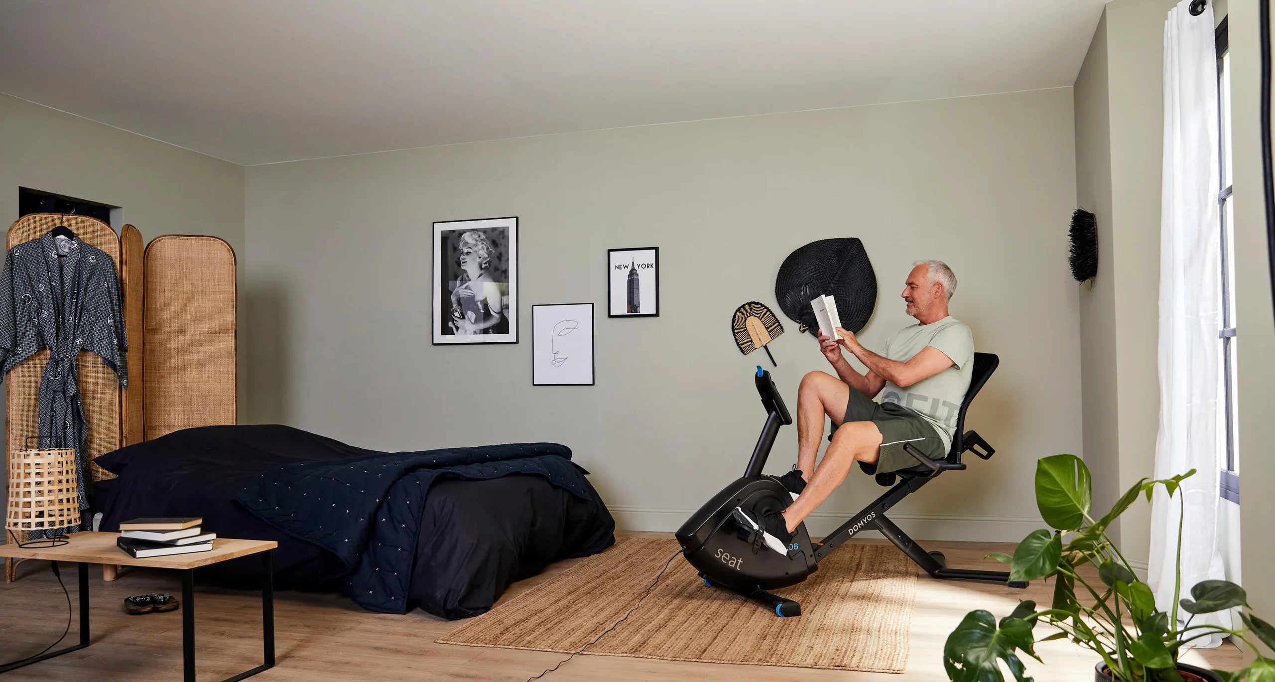 Man reading a book while pedalling a recumbent bike at home