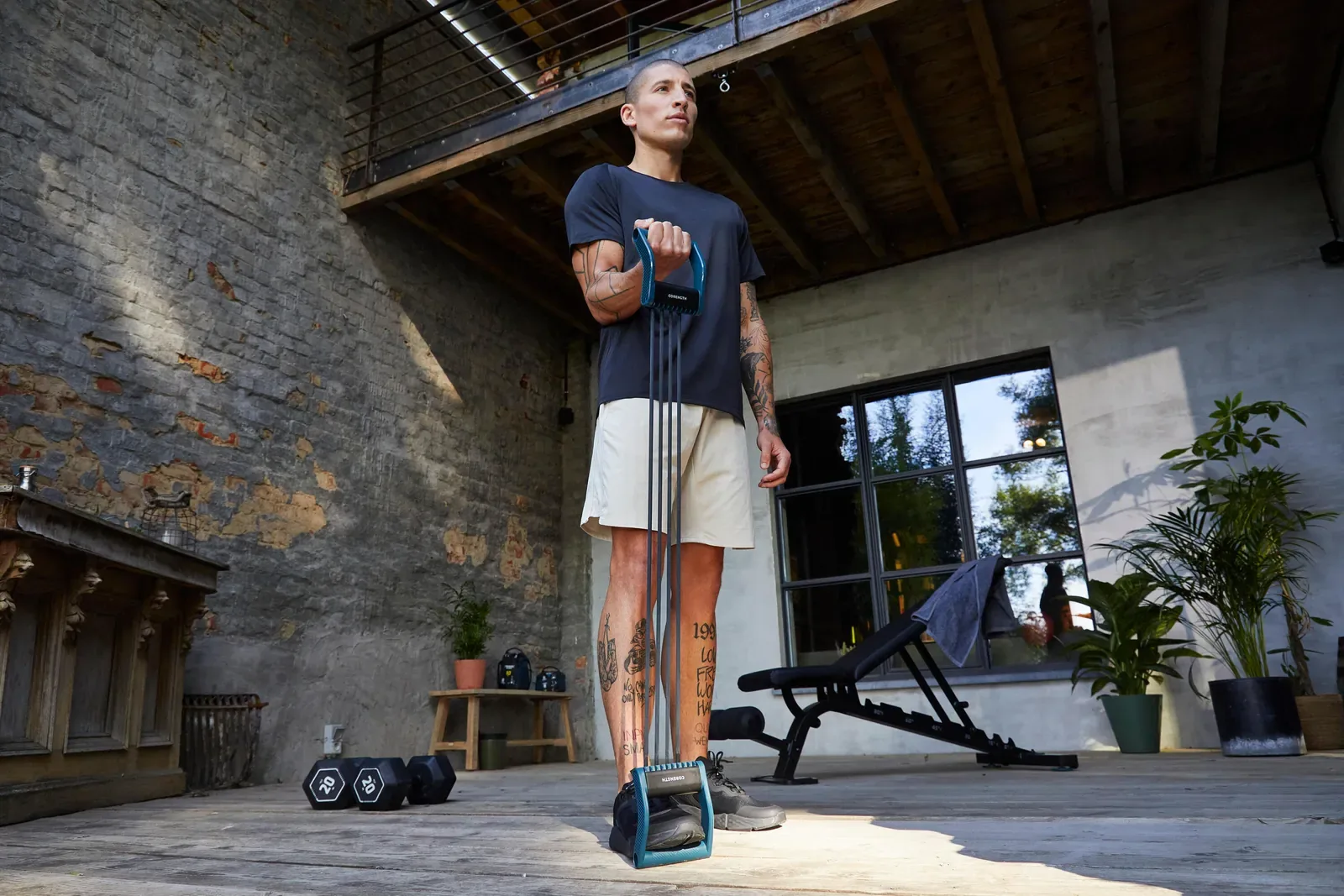 Man doing a standing resistance band pull in a home loft workout space
