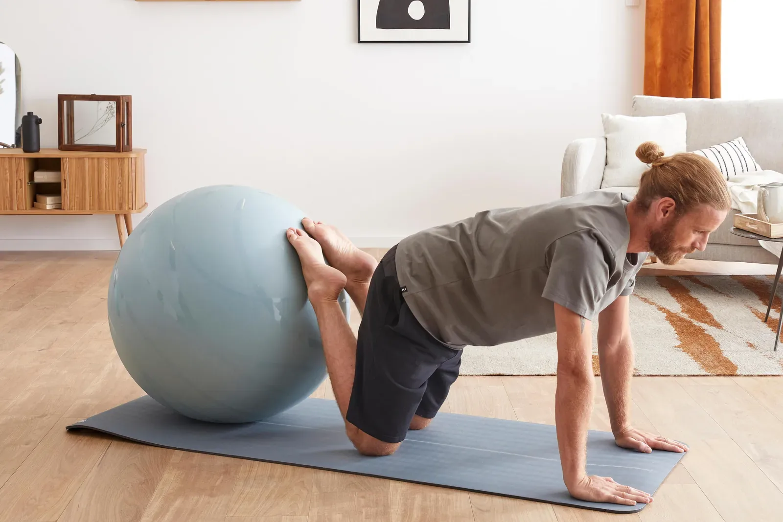 Man stretching on an exercise mat with a stability ball in his living room