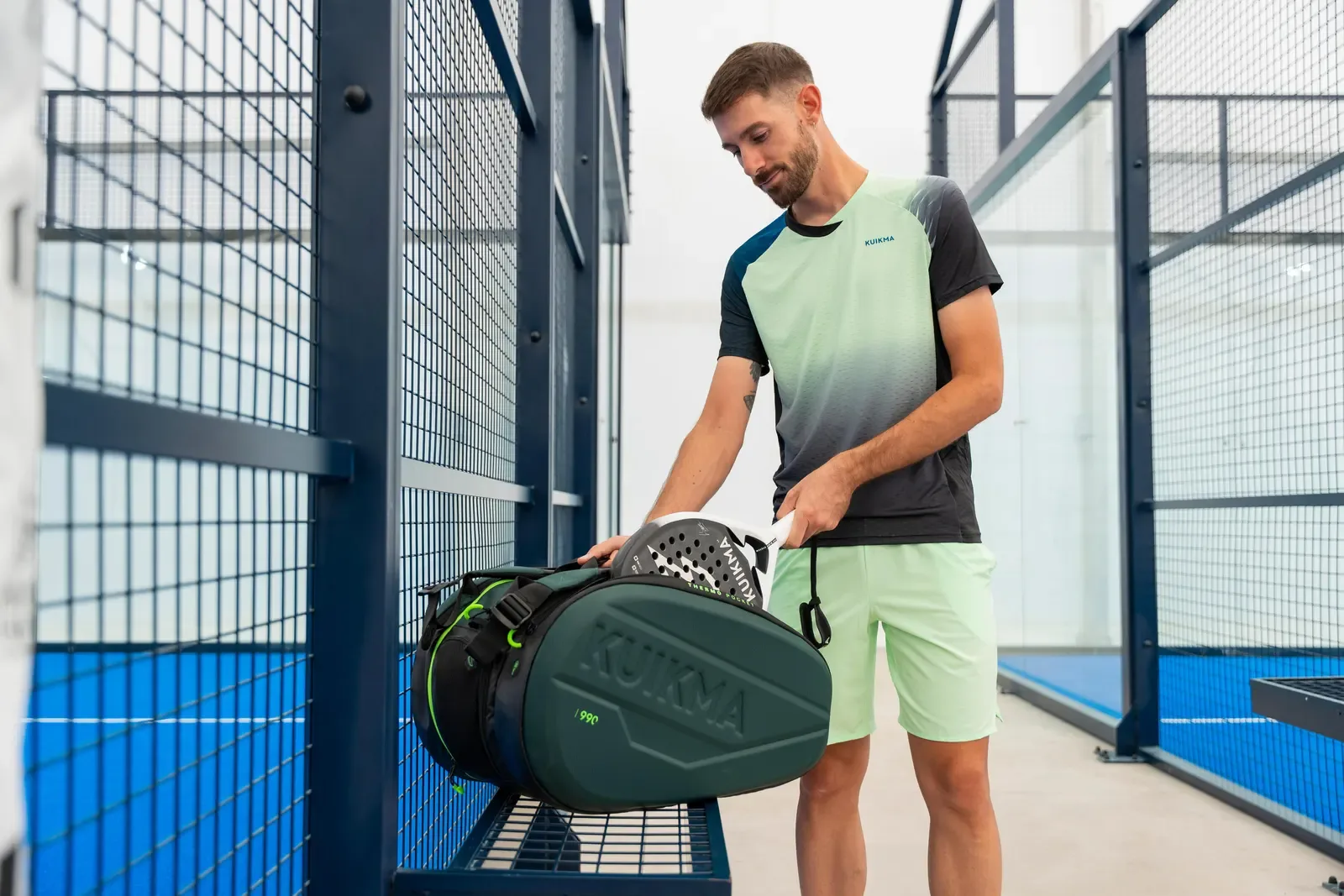 Padel player packing his racket into a bag beside the court