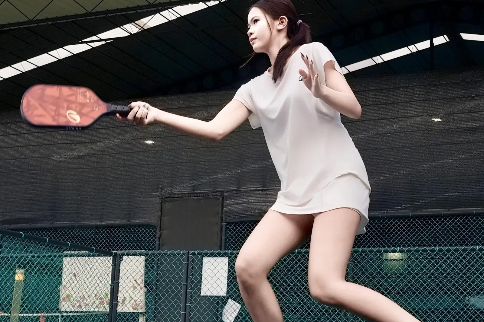 Pickleball player reaching for a forehand on a covered court