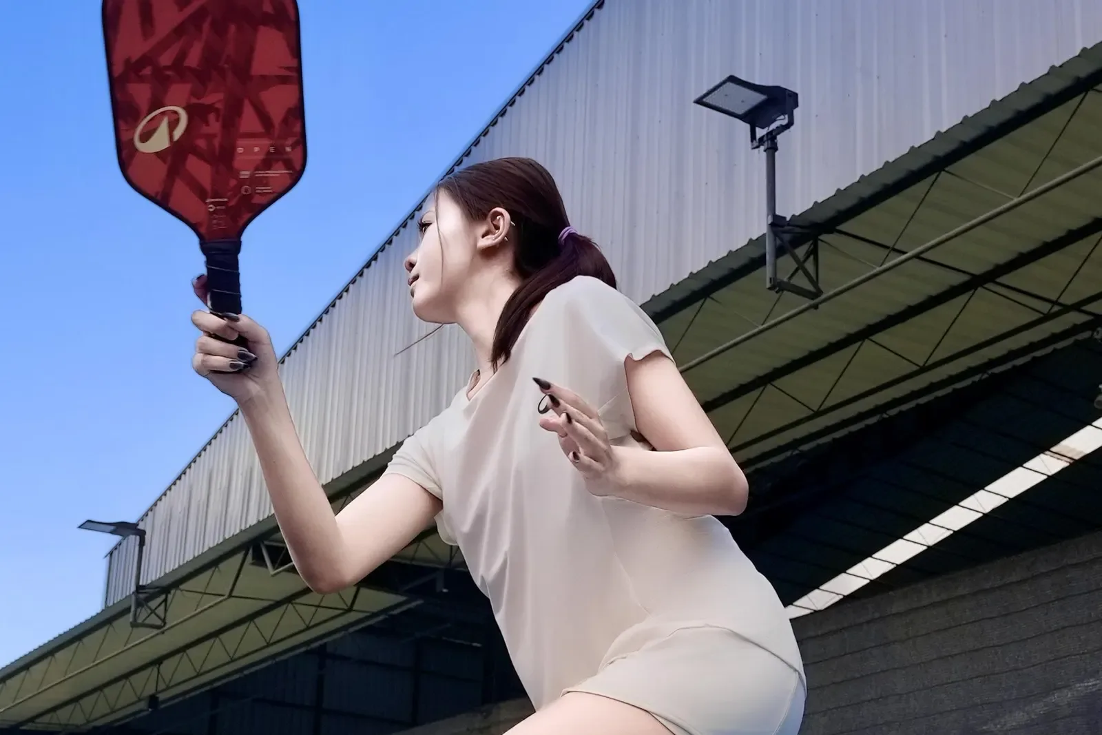 Pickleball player with paddle raised, ready to hit on an outdoor court