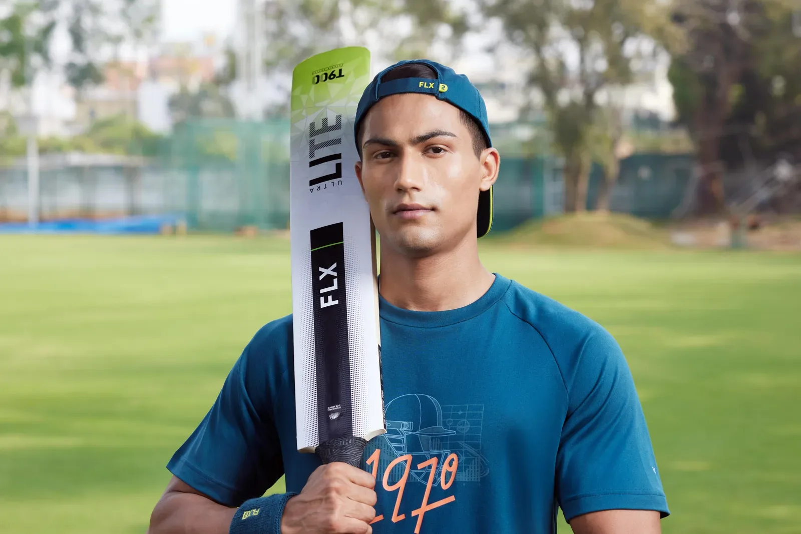 Cricketer on a cricket ground holding a bat over his shoulder