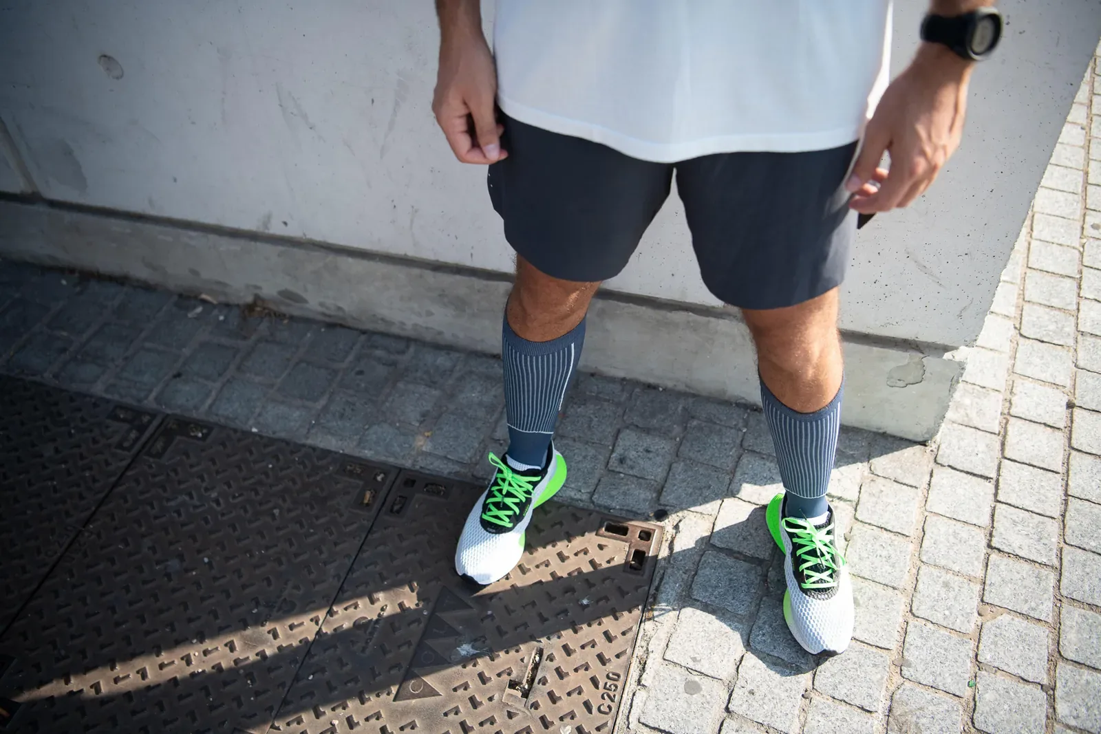 Runner in compression socks standing on a city footpath to cool down after a run