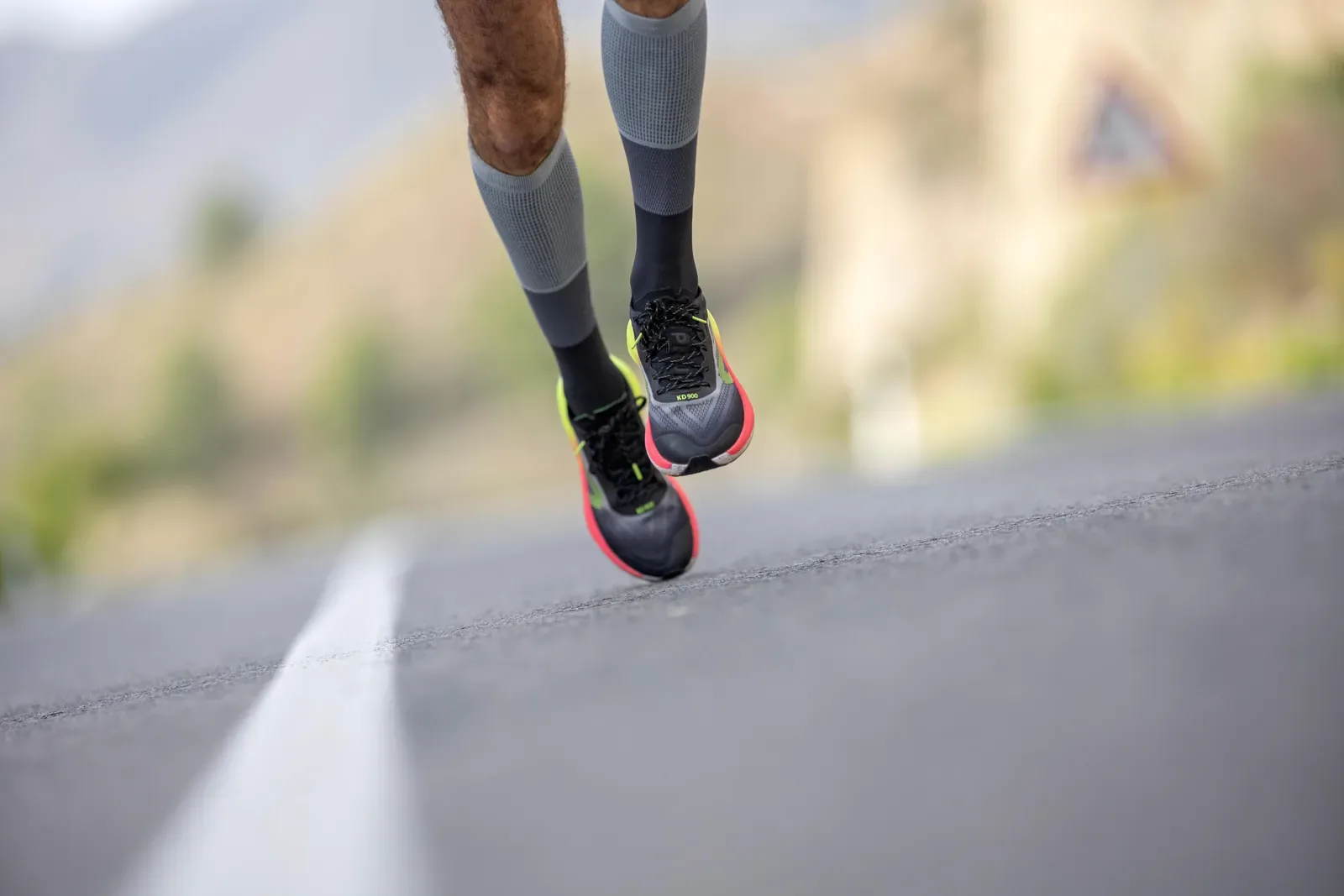 Close view of a runner's legs and shoes striding along an open road
