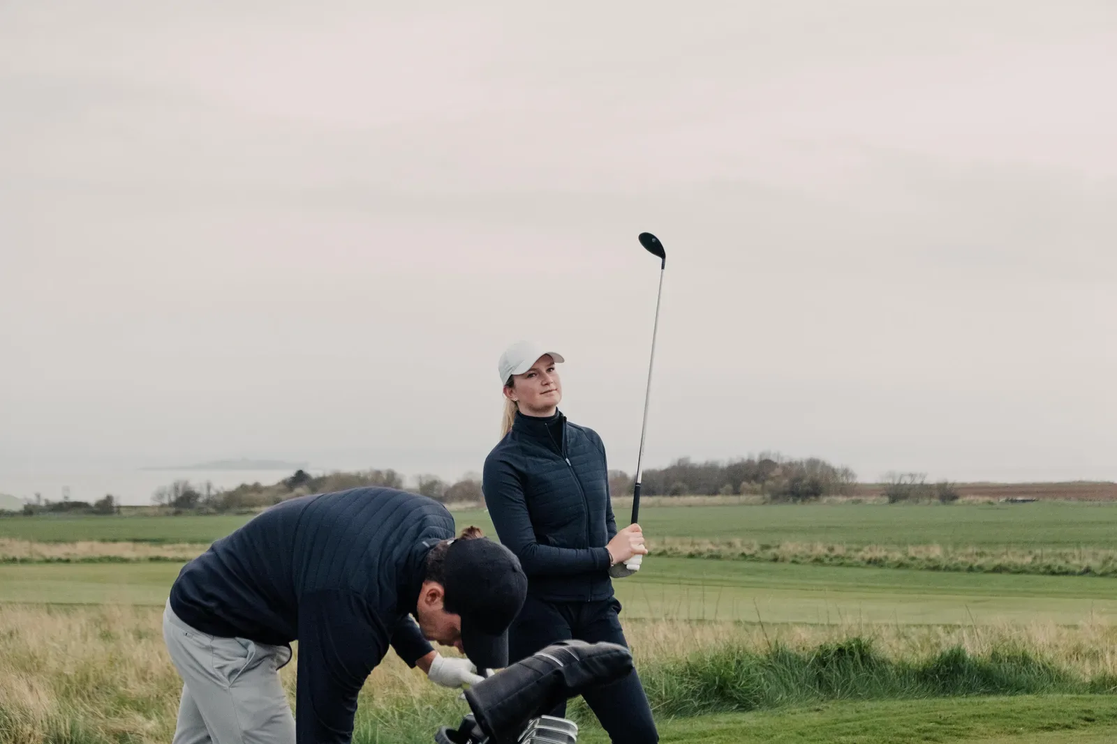 Two golfers by their bag on a links course near the coast