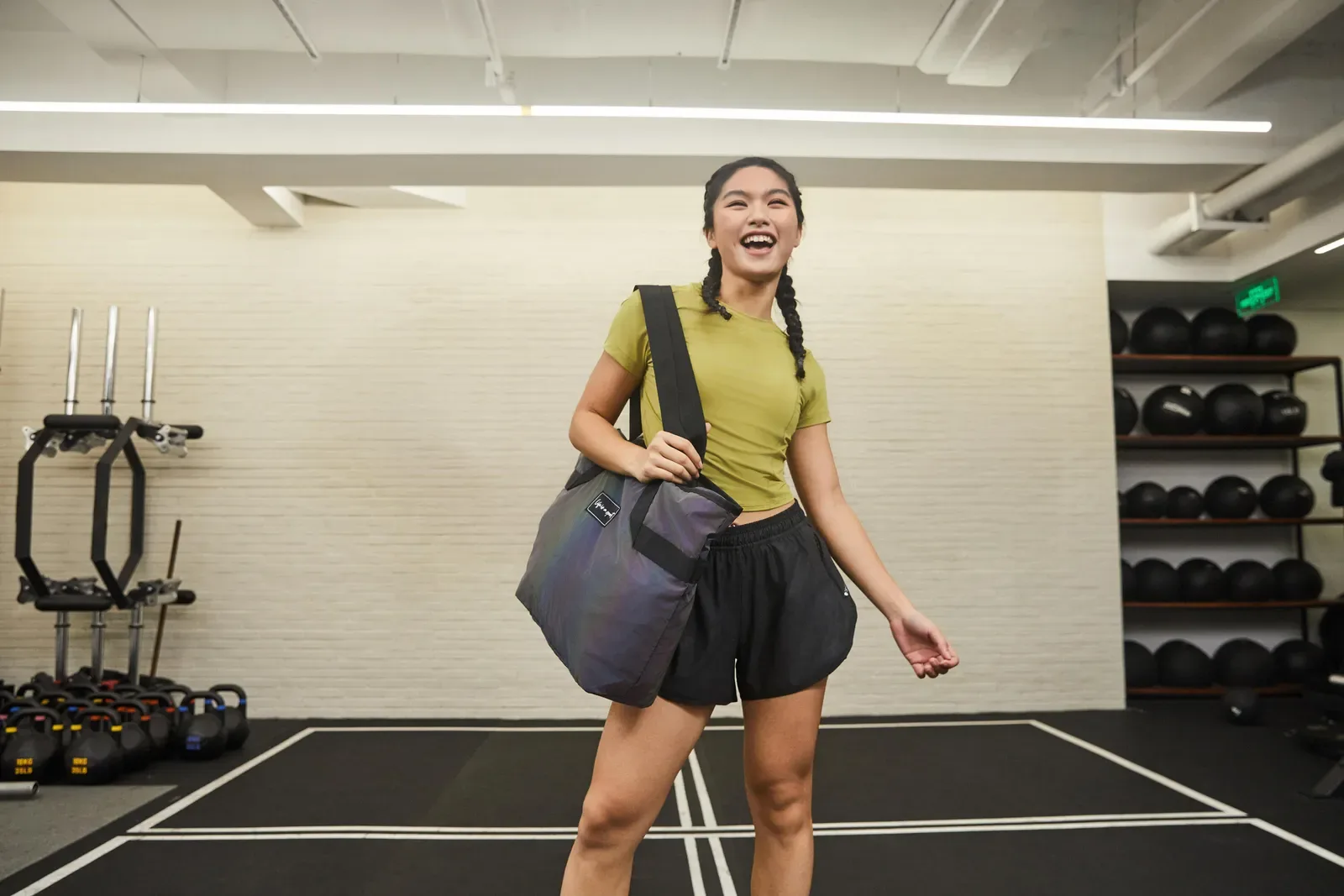 Smiling woman arriving at the gym with a duffel bag over her shoulder