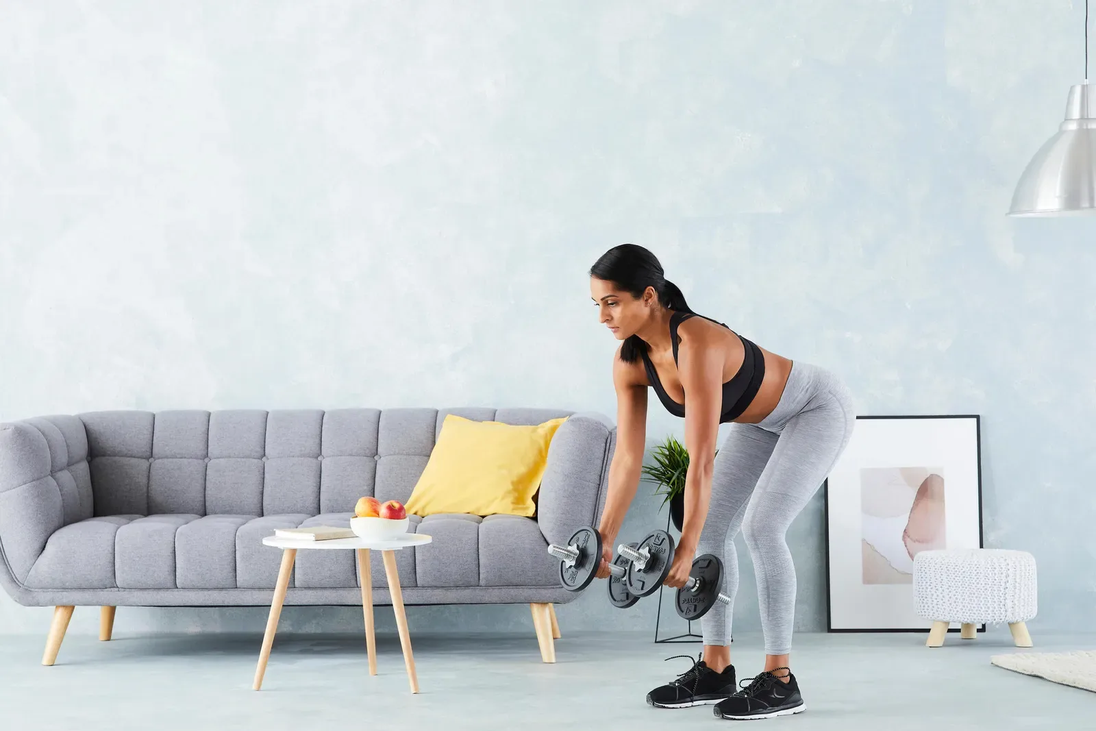 Woman doing a bent-over dumbbell row in her living room