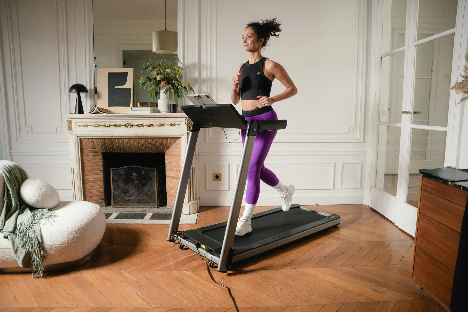 Woman walking on a compact treadmill in a bright living room